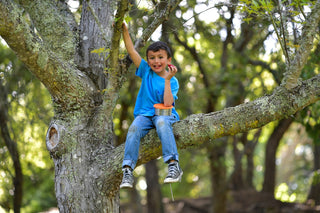 a young boy sitting in a tree talking on a cell phone