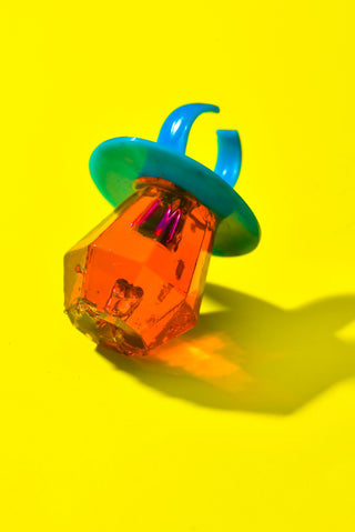 a plastic object sitting on top of a yellow surface