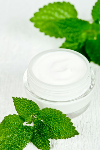 A jar of cream next to some mint leaves