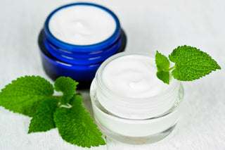 A jar of cream next to a green leaf