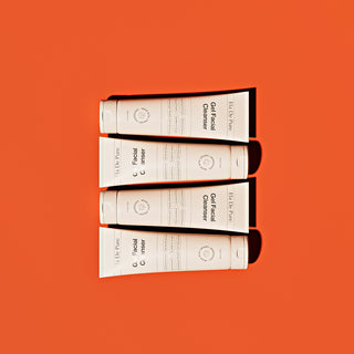 Four tubes of facial cleanser on orange background