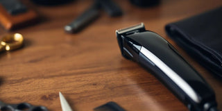 Modern hair clipper on wooden surface with grooming tools.