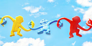 three assorted-color monkey plastic toys holding each other during daytime