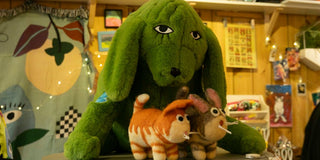 a green stuffed animal sitting on top of a table